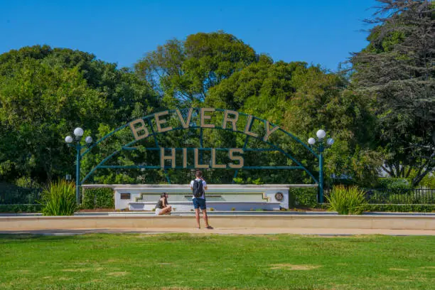 Tourists taken pictures at Beverly Hills Sign , sunny summer day with green trees and blue sky