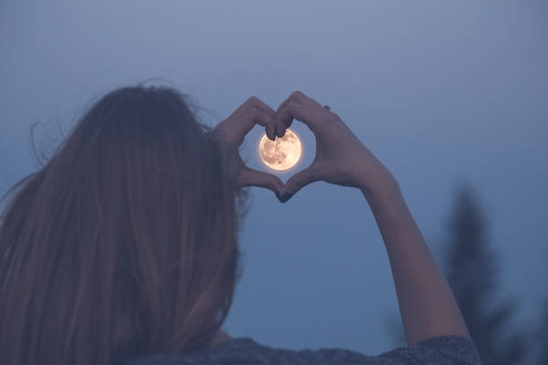 Love and moon creative concept. Woman making heart shape with her hands over full moon. full moon stock pictures, royalty-free photos & images