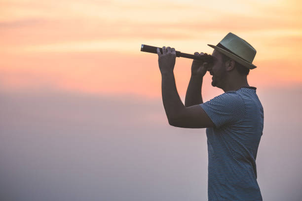 istock Side view of young hipster guy using spyglass outdoors. 956988812