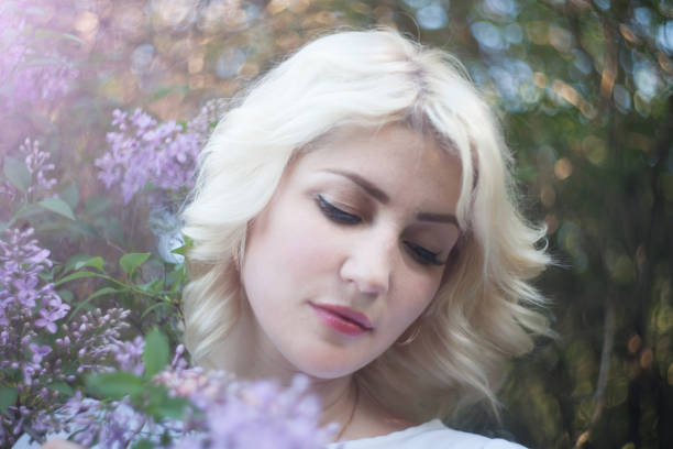 istock Beautiful woman in a spring garden with blooming lilacs 956989934