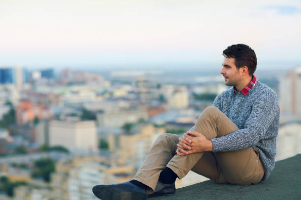 istock Young man sitting outdoors on the roof 957001798