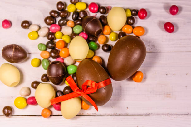 istock Chocolate easter eggs and multicolored candies on wooden table. Top view 957002588