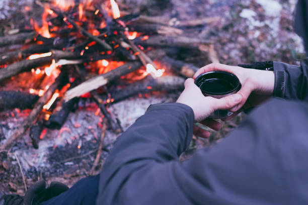 istock Man traveler hands holding cup near the fire 957005660