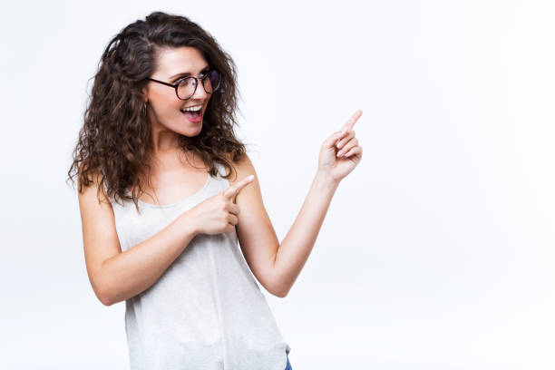 istock Beautiful young woman showing and pointing over white background. 957006094