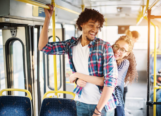 istock Young beautiful charming girl is displaying affection toward her handsome young boyfriend trough the hug as they stand on the bus. 957006380