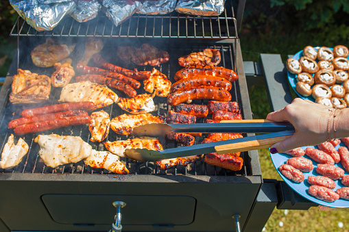 Grilling food on barbecue grill, hands preparing skewers