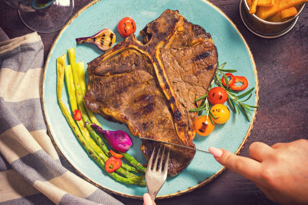 티 본 스테이크 육즙을 먹는 젊은 여자 - rib eye steak steak beef prepared potato 뉴스 사진 이미지