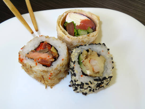 istock Sushi rolls with chopsticks on white plate. Japanese food 957016388