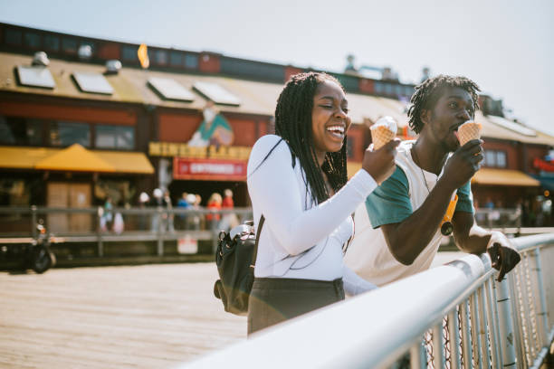 Couple Enjoying Ice Cream on Seattle Pier A cute young man and woman enjoy a tasty ice cream waffle cone on a sunny day in downtown Seattle. seattle photos stock pictures, royalty-free photos & images