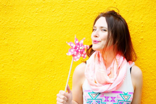 istock young woman standing at yellow wall with pinwheel 957023664