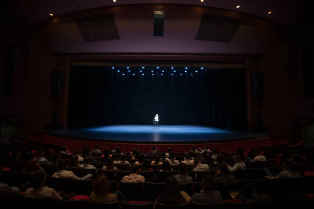 Audience enjoying a singing performance on stage Audience enjoying a singing performance on stage at the theater incidental people photos stock pictures, royalty-free photos & images