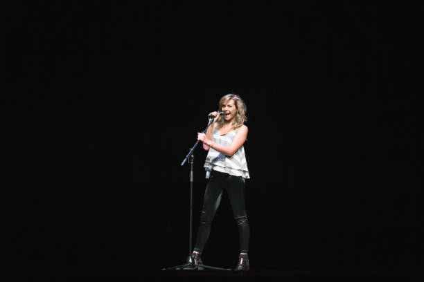 istock Beautiful female singer holding the microphone stand and singing 957023800