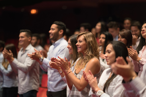 People at a ballet performance applauding and smiling in a theater