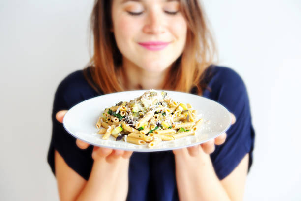 młoda kobieta trzymająca biały talerz z makaronem i serem - pesto sauce italian culture pine nut photography zdjęcia i obrazy z banku zdjęć