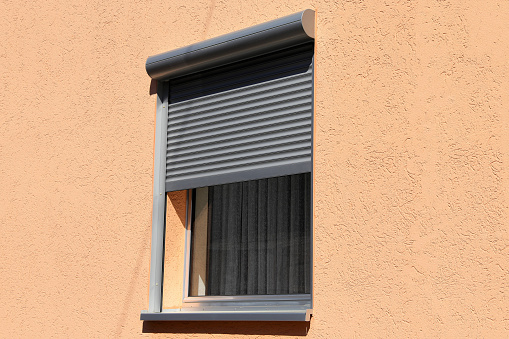 Section of an old brown brick wall with a protected window.