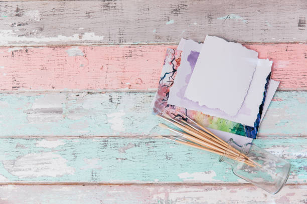 istock Paint brushes and empty watercolour paper on shabby chic background. Art workspace. Top view, copy space 957030632