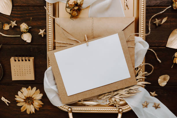istock Empty greeting card with kraft envelope and gold decorations  on wooden background. Wedding concept. Top view, flat lay 957031376