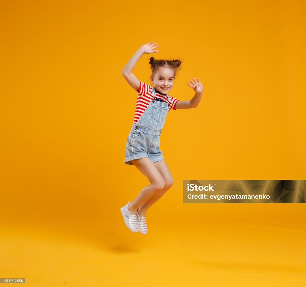 funny child girl jumping on colored yellow background funny child girl jumping on a colored yellow background Child Stock Photo