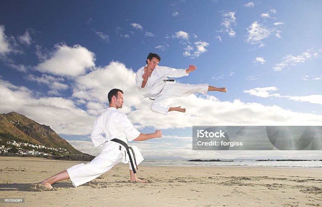 Hombres practicar Karate en la playa - Foto de stock de Patada voladora - Artes marciales libre de derechos