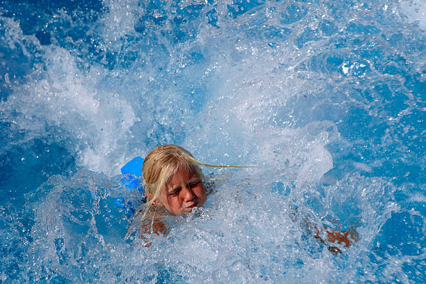 istock blond girl splashing in a swimming pool 95706804