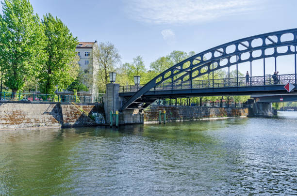 Banks of the river Spree with the footbridge Gerickersteg in the city center of Berlin in spring Berlin, Germany - April 22, 2018: Banks of the river Spree with its arched footbridge Gerickersteg and pedestrians on it  in the city center in springtime. moabit stock pictures, royalty-free photos & images