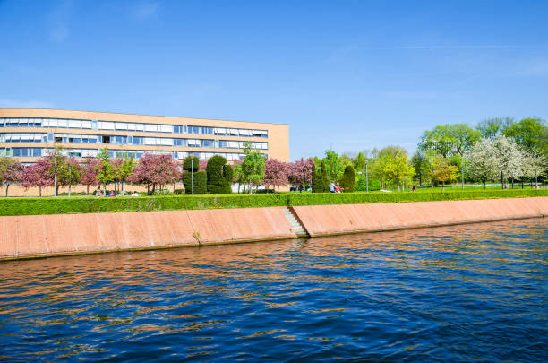 Magnus-Hirschfeld-Ufer with flowering trees, waterfront promenade and Federal Snake Complex in Berlin Berlin, Germany - April 22, 2018: One of the banks of the river Spree Magnus-Hirschfeld-Ufer with flowering trees, waterfront promenade and the last segment of The Snake or Federal Snake Complex, apartment building complex in Moabit Werder district moabit stock pictures, royalty-free photos & images