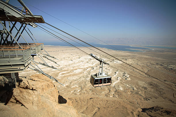 The gondola moves along a cable above the ocean at dusk
