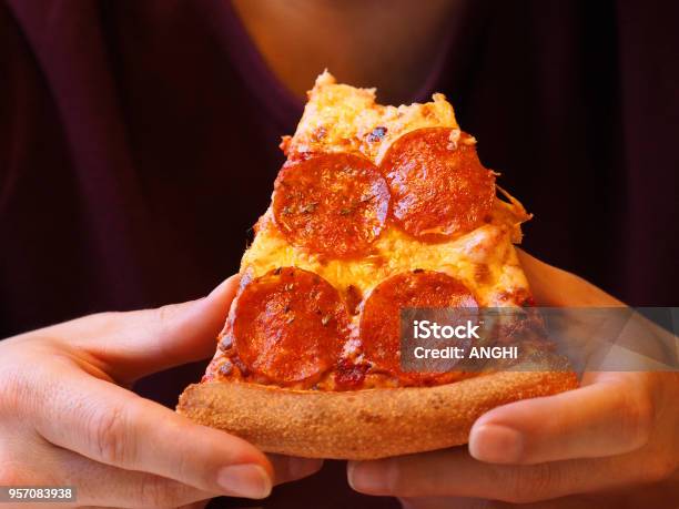 Fetta Morsa Di Pizza Nelle Mani Della Persona Da Vicino Luomo Con Una Maglietta Viola Con Le Mani Ben Curate Sta Mangiando Pizza Pepperoni - Fotografie stock e altre immagini di Pizza