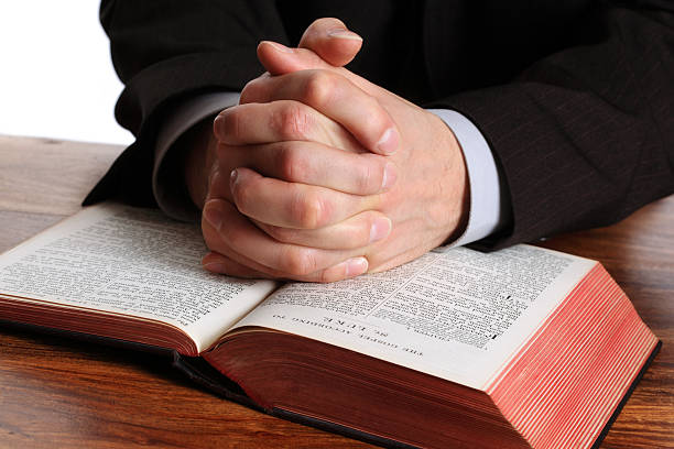 rezar sobre una biblia abierta manos - praying human hand worshipper wood fotografías e imágenes de stock