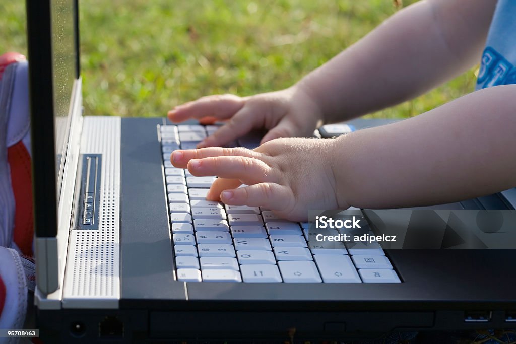 Bambina mani digitando sulla tastiera del computer portatile - Foto stock royalty-free di Bambino
