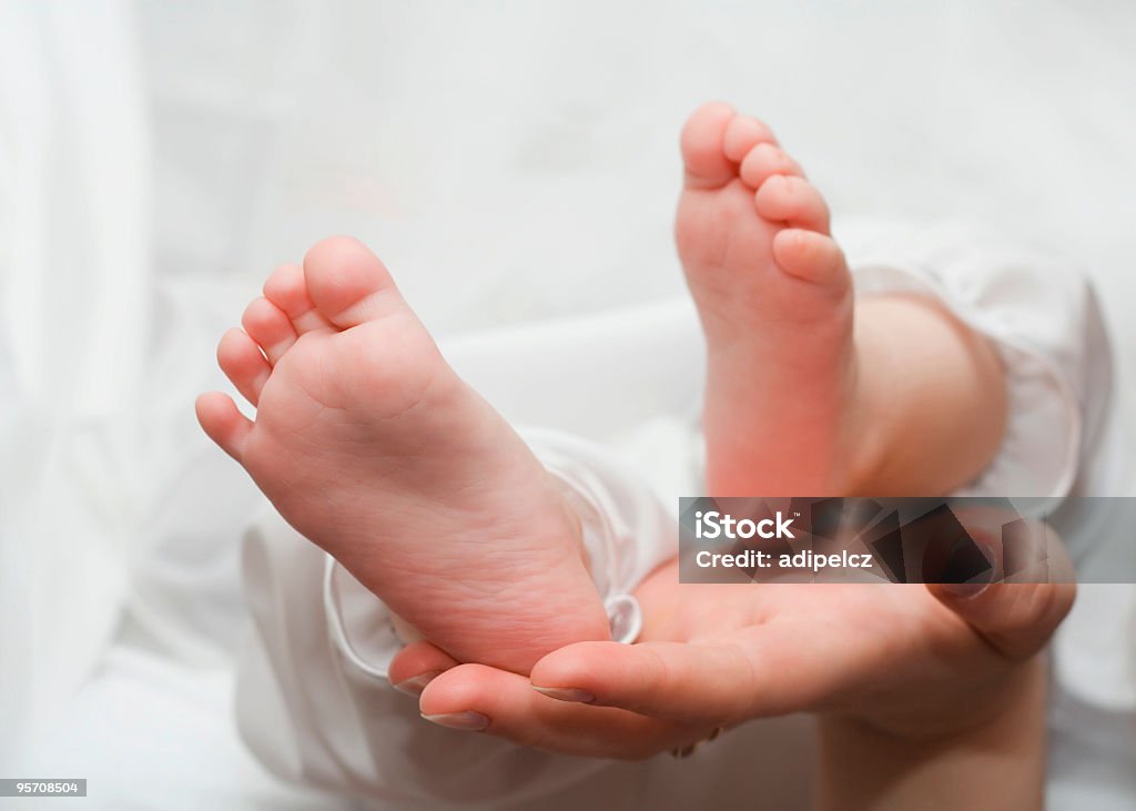 Piedi del bambino tenuti in mano - Foto stock royalty-free di Accudire