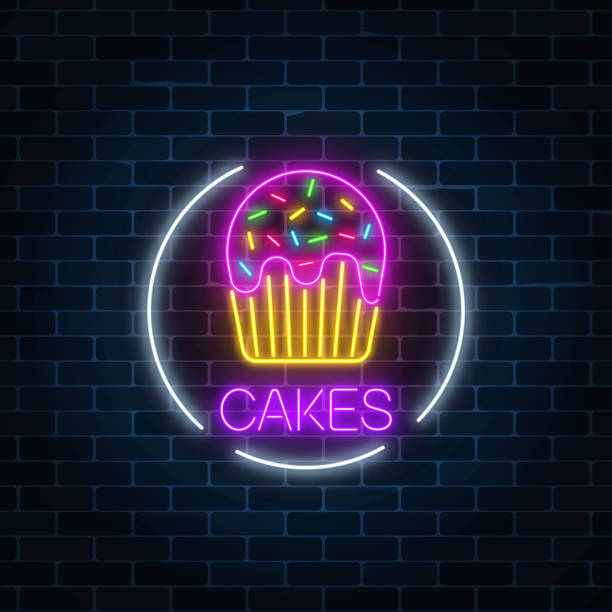 istock Neon glowing sign of cake with glaze in circle frame on a dark brick wall background. 957087228