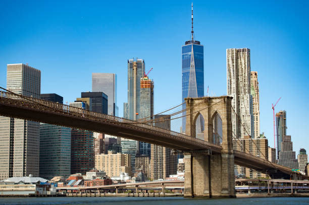 manhattan skyline with the brooklyn bridge and the one world trade center in the background during a sunny day in new york, usa. - brooklyn brooklyn bridge new york city skyline imagens e fotografias de stock