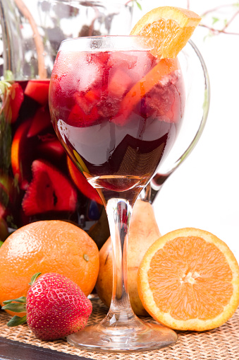 Vertical frame of wine glass full of sangria sitting with pitcher and fresh fruit; copy space 