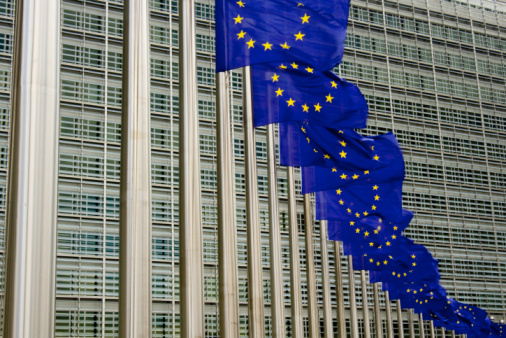 blue EU flags with its stars in Brussels in front of European Commission and Parliament