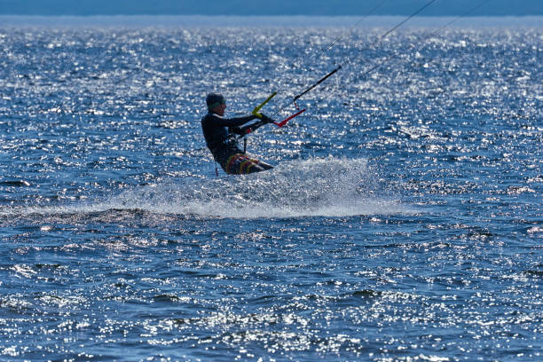 istock A male kiteboarder rides on a board on a large river. He performs various exercises while moving on water. Splashes of water scatter in different directions. The sun's rays shine in the water. Sunny spring day. 957115630