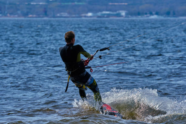 istock A male kiteboarder rides on a board on a large river. He performs various exercises while moving on water. Splashes of water scatter in different directions. The sun's rays shine in the water. Sunny spring day. 957115694