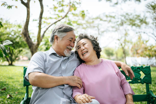 healthy senior couple relaxing  seats on the bench in the park stock photo