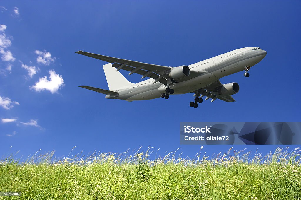 Avião voando em um céu azul e verde grama - Foto de stock de Aeroporto royalty-free