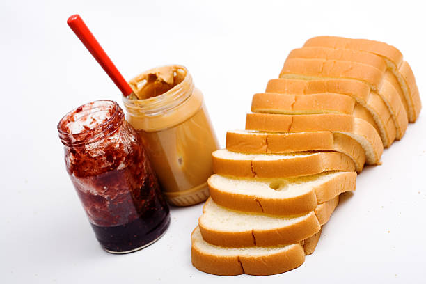High angle view of three different preserves on slice of bread over pink background