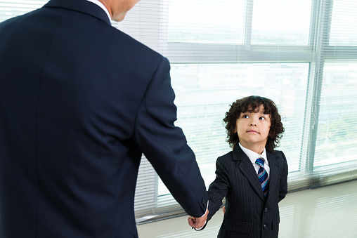 The boy in a suit handshake with businessman