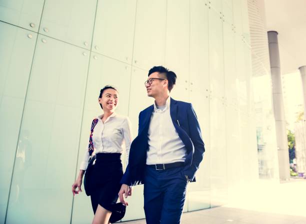 istock Asian business people discussing while walking 957135328