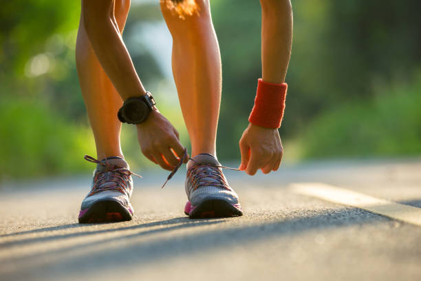 istock woman runner tying shoelace before run on forest trail 957143596