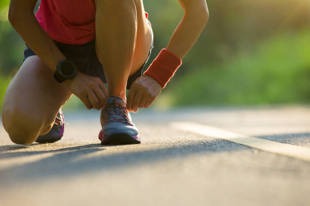 istock woman runner tying shoelace before run on forest trail 957143750