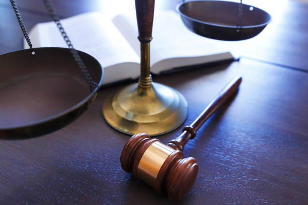gavel отдыхает перед шкалой правосудия и открытой книгой закона - иск стоковые фото и изображения