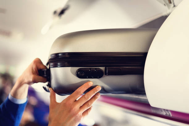 compartimiento de equipaje de mano con las maletas en el avión. manos sacan el equipaje de mano. pasajero pone cabina bolsa de cabina en el estante superior. concepto de viaje con espacio de copia - equipaje de mano fotografías e imágenes de stock