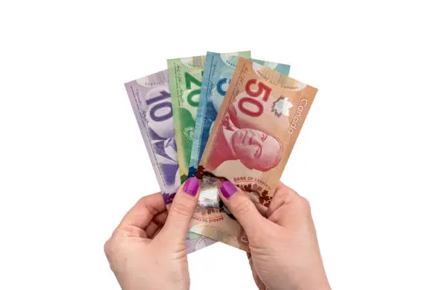 Photo of Canadian dollar on female hand isolated on white