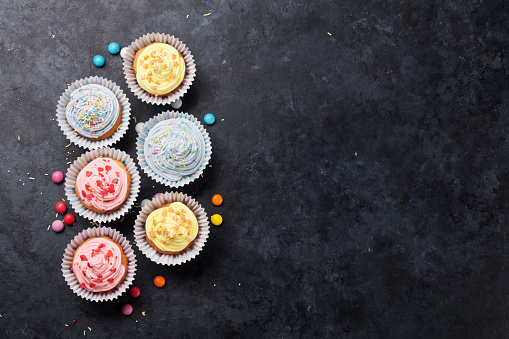 Sweet cupcakes with colorful decor and candies. Top view with space for your greetings