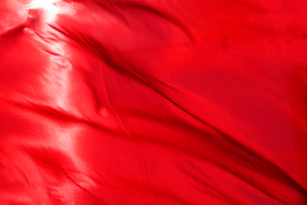 istock Red cloth or silk flag waving at wind. Holiday background. 957163026