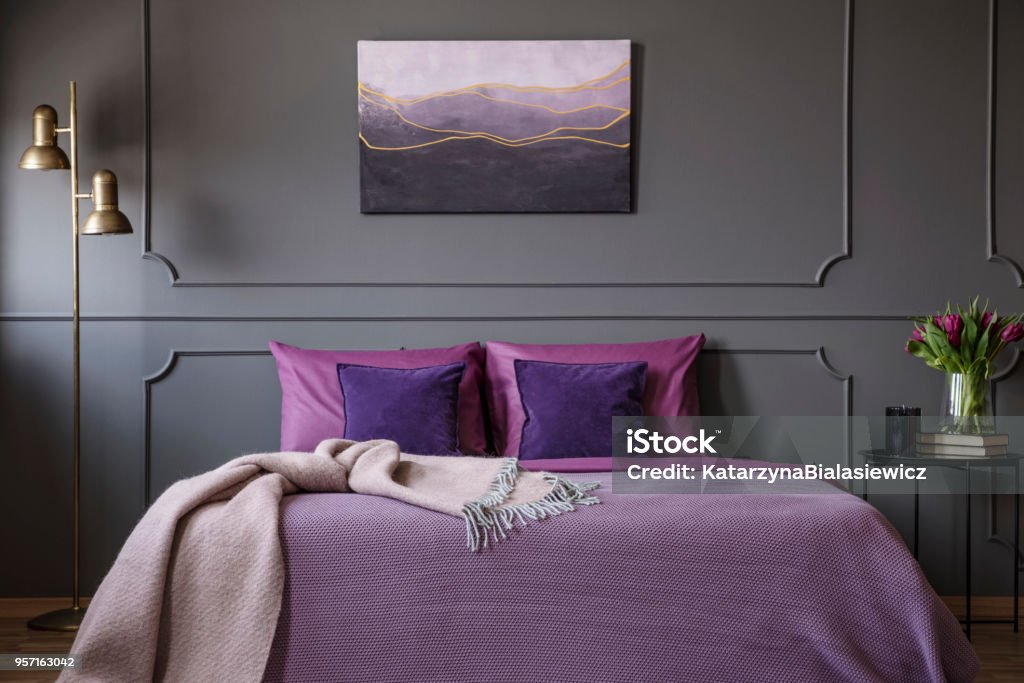 Elegant violet bedroom interior Pink blanket on violet bed in elegant bedroom interior with painting on grey molding wall Purple Stock Photo